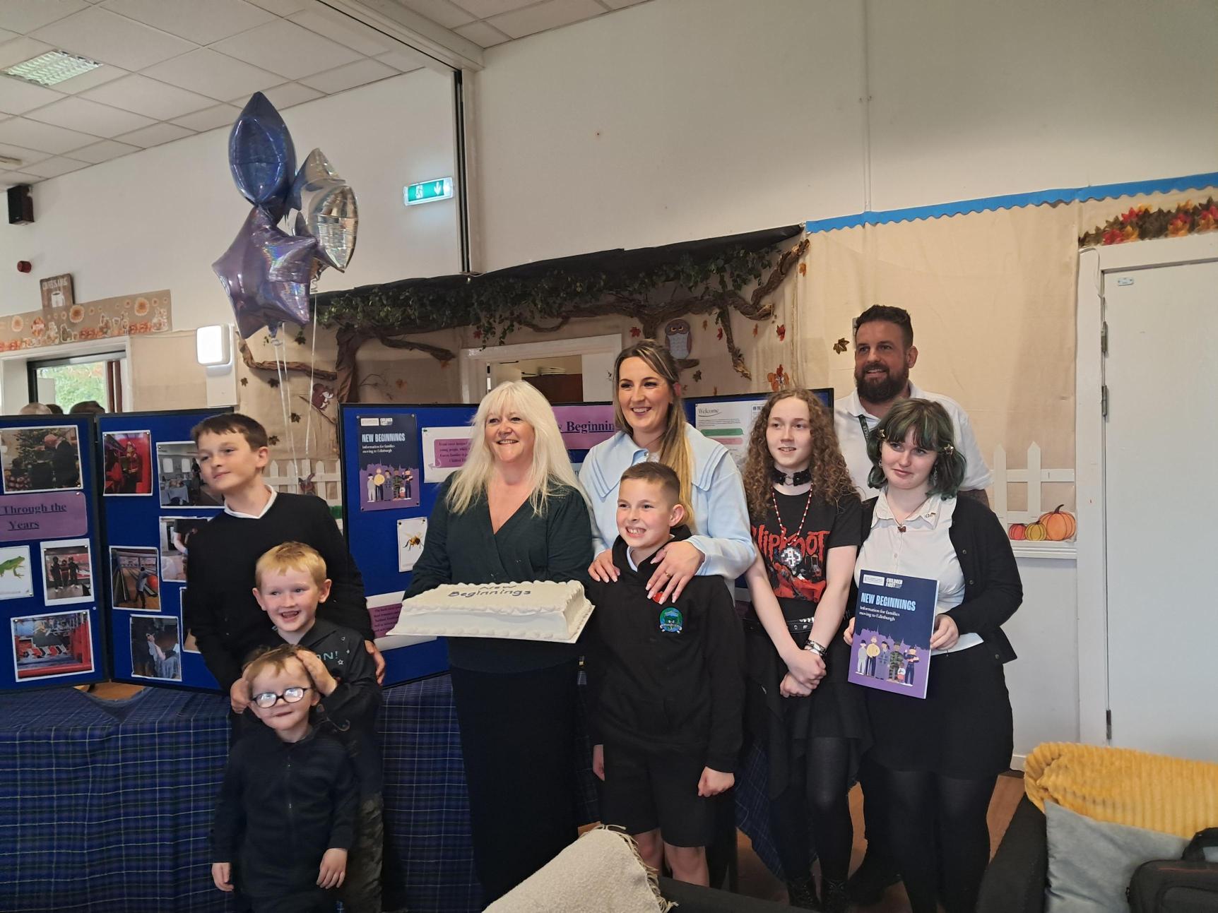 Families celebrating the launch of the map with a cake that reads 'new beginnings'